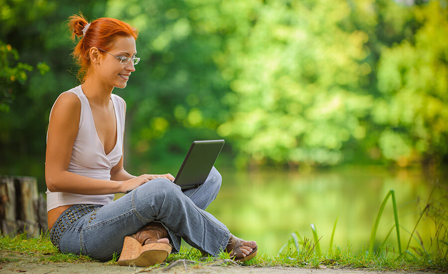 Redhead with laptop by pond