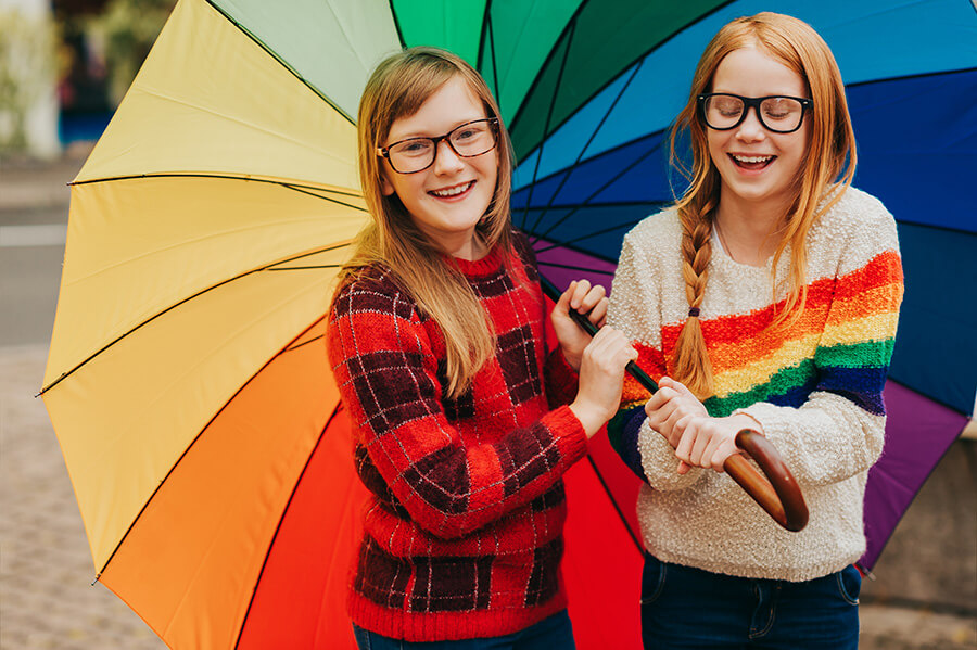 Friends holding rainbow umbrella